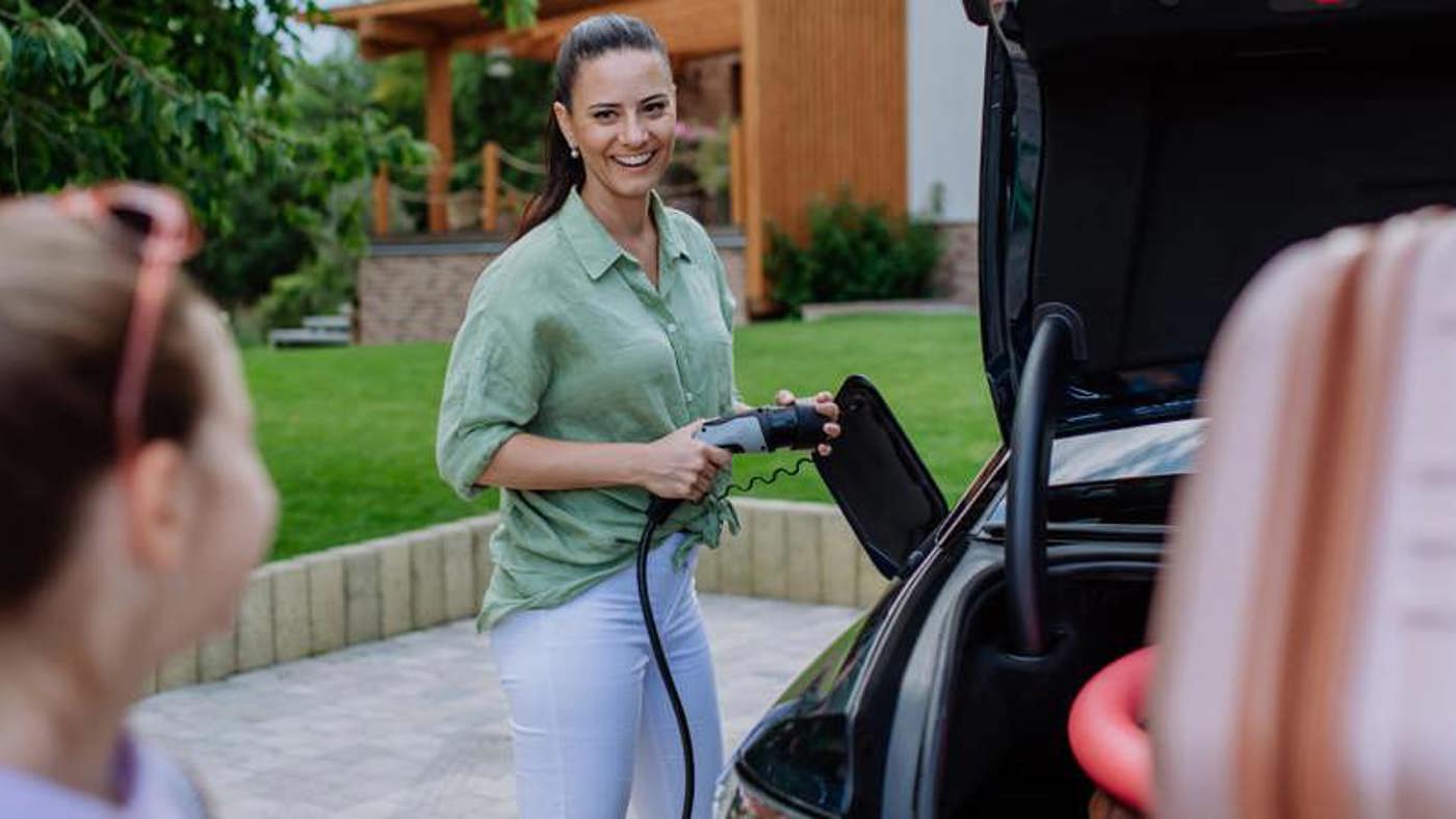 a woman user her home EV charger on her electric vehicle