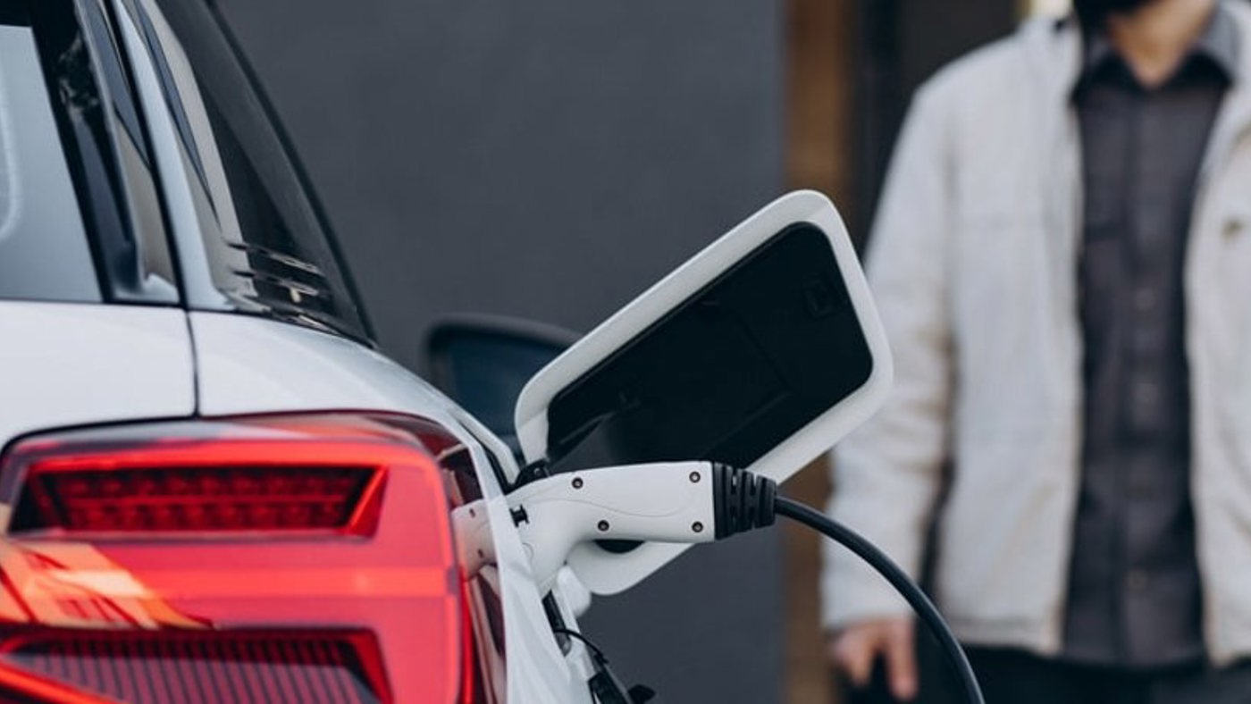 Man standing in background of EV vehicle being charged