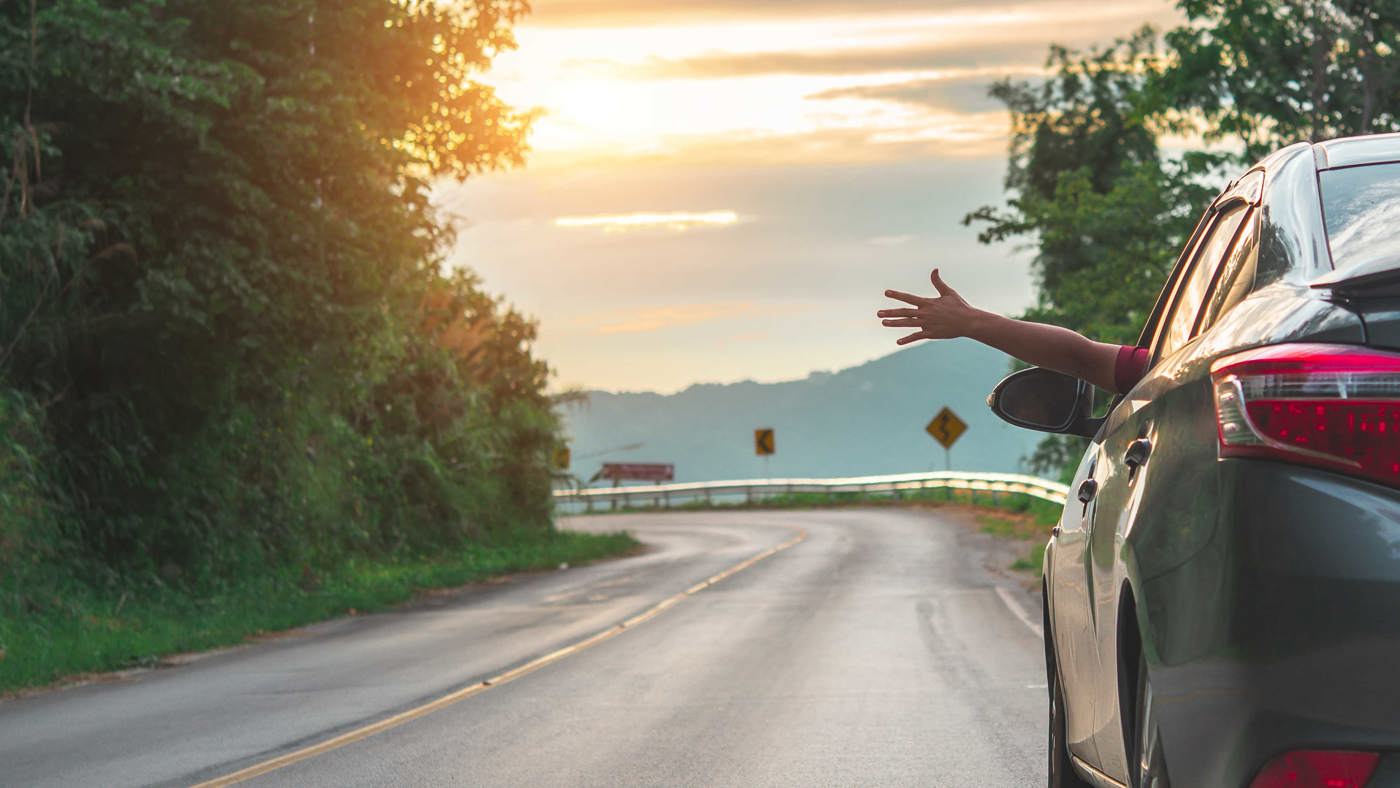 EV driving along country road with persons arm stetched out of the car window