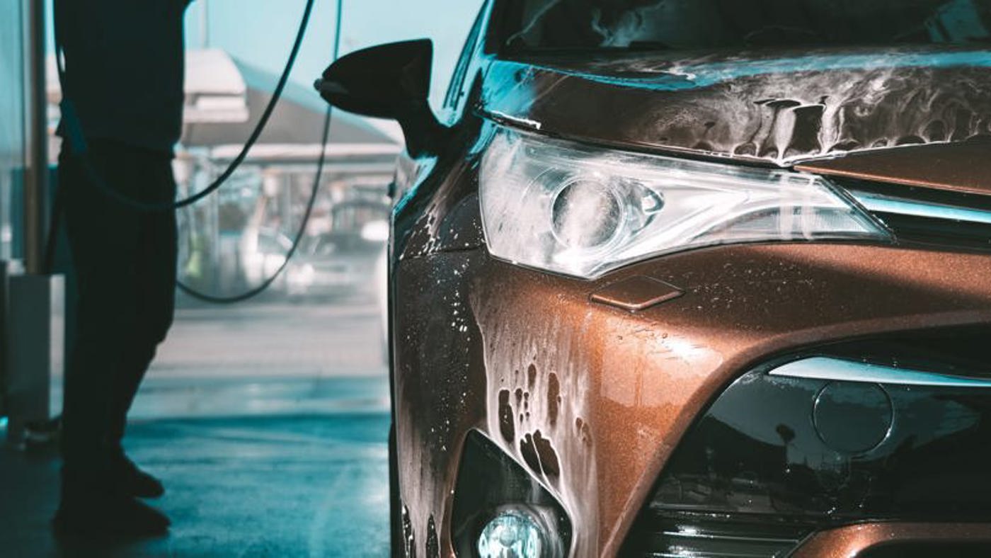 Man spraying car with pressure washer.