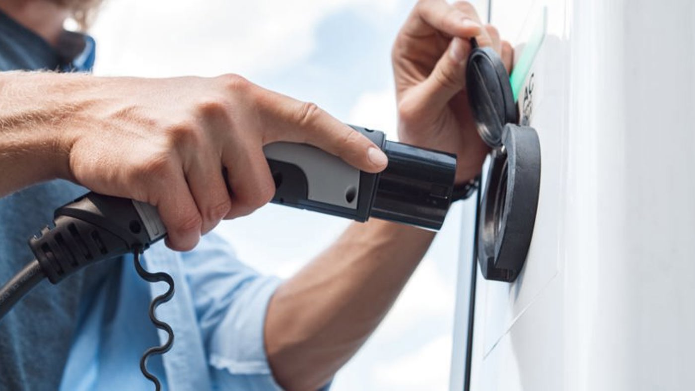 Man plugging in to charge electric vehicle.