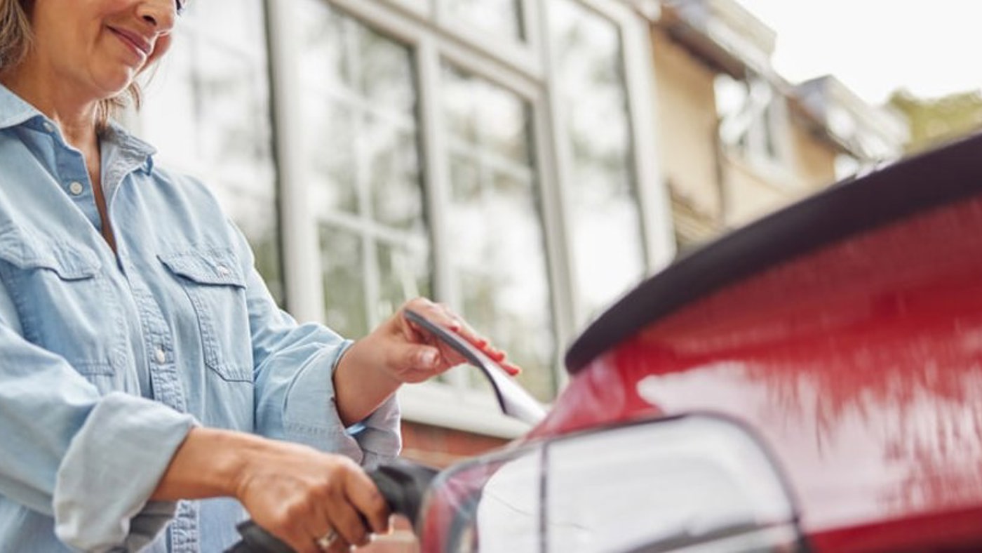 woman charging EV car outside house