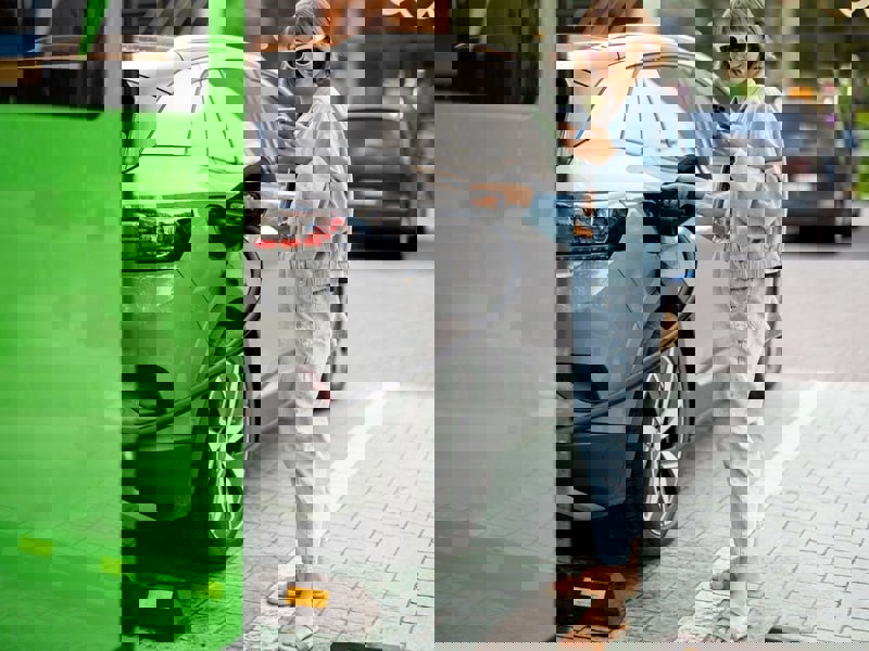 Woman charging her electric vehicle in public.