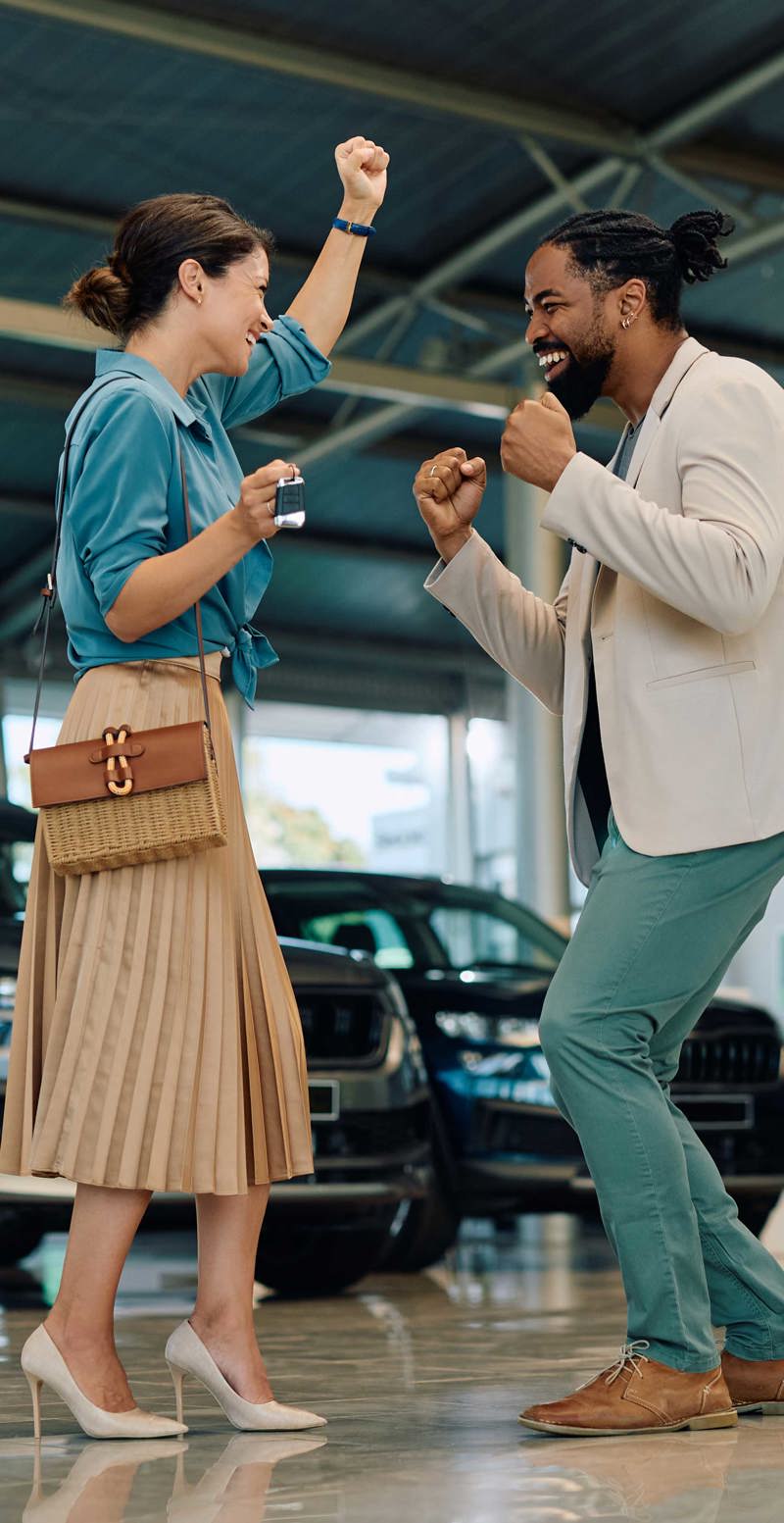 Two people dancing in a car dealership with the words 'more sales' in the background